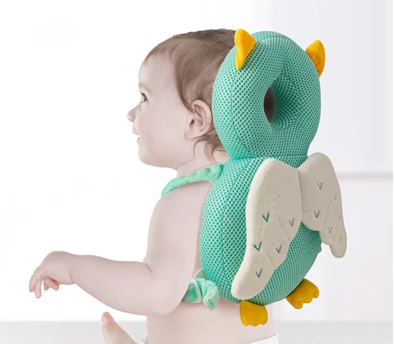 Baby sitting up wearing the green owl LittleTumble Backpack
